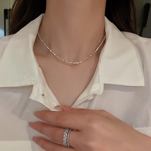 Macro shot of silver minimalist irregular geometric necklace and pavé band ring on a model