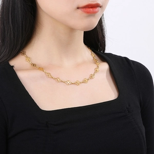 Close-up of golden hollow clover necklace on model neck showing elegant details