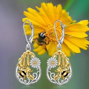 Primer plano detallado de los pendientes de abeja y margarita con baño bicolor plata y oro