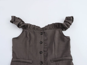 Dettaglio top grigio scuro con balze, spalle scoperte e bottoni frontali classici