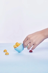 Close-up of S925 sterling silver rainbow zircon rings worn on hand with blue cup
