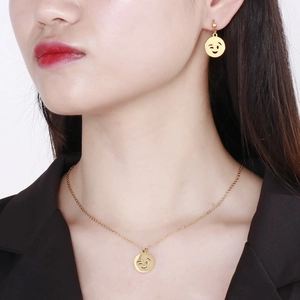 Golden stainless steel smiley face necklace and earrings set worn by a fashion model