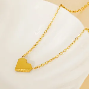 Elegant 18k gold plated heart pendant necklace with textured edges on white shell plate