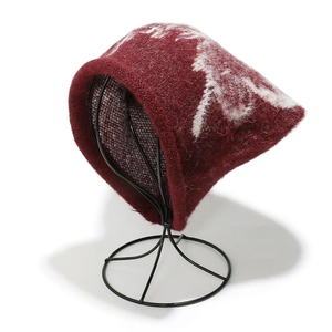 Detailed view of dark red knit beanie with white abstract pattern and plush mohair texture