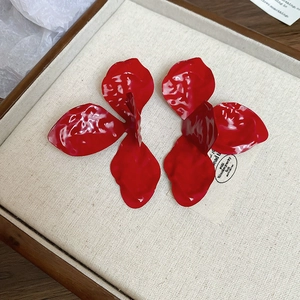 Macro shot of red lacquered flower earrings with realistic petal texture on a tray