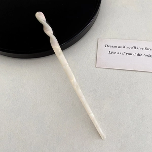 Detail view of pearl white acetate hair stick with elegant marble texture and twisted design