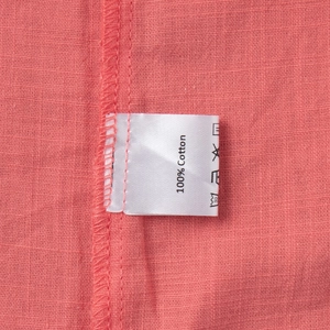 Detail view of 100% cotton fabric with neat stitching and clothing care label on pink shirt