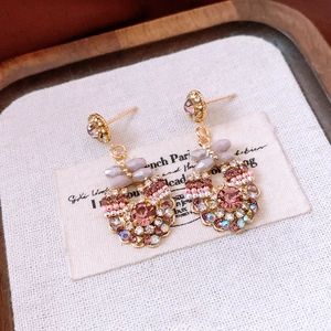 Close-up of vintage gold-plated earrings with pink crystals on rustic linen fabric