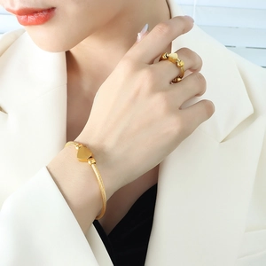 Elegant gold cable jewelry set featuring heart charms and beads worn by a model