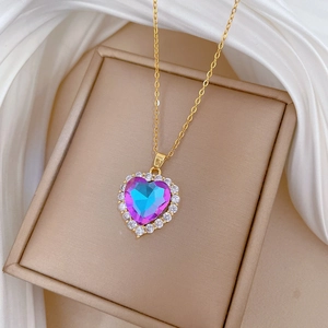 Detail of heart pendant with purple gradient gemstone and gold chain on silk