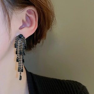 Detail of long black tassel earrings with dark rhinestones on a side-view model