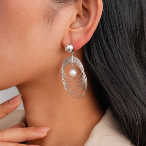 Detailed view of multilayer silver hoops with a centered pearl on a fashion model