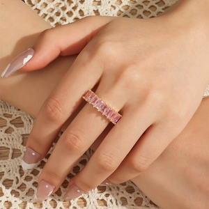 Macro shot of gold orbital ring with pink rectangular zircon stones on lace background