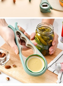 Green 4-in-1 multi-functional jar opener being used to open a pickle jar in a kitchen