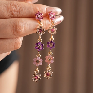 Detail of gold flower tassel earrings with pink and purple crystal gradient stones