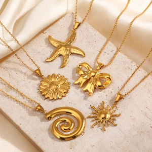 Set of five gold starfish, sunflower and bow pendants on beige textured stone and silk