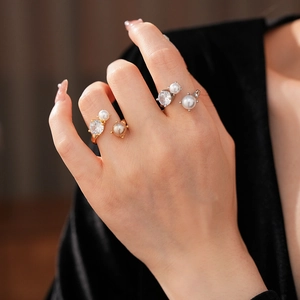 Détail de bagues en or et argent avec zircon rond et perles sur une main
