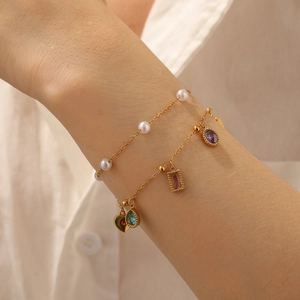 Close-up of double-layer gold bracelet with colored gemstones and pearls on wrist