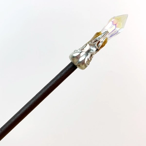 Macro detail of fairy wand hair stick with a faceted iridescent crystal on dark wood handle