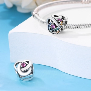 Detailed macro shot of silver bead charms with pink crystals on a snake chain bracelet