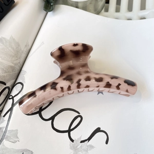 Close-up of pink leopard print hair claw clip on a magazine showing glossy resin texture