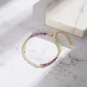 Detail of freshwater pearl bracelet with purple stones and gold clasp on marble background
