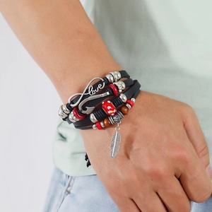 Detail eines Boho-Lederarmbands mit silbernen Federn und Unendlich-Liebe-Anhängern