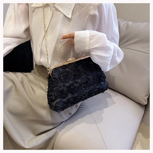 Detail of 3D rose fabric texture on black evening bag with gold metal handle and crystals