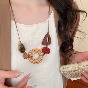 Detailed close-up of Bohemian rattan pendant necklace with amber resin and wood beads