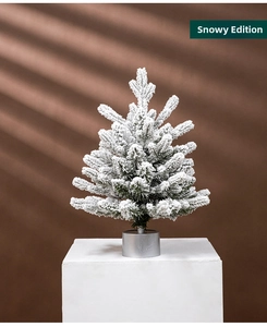 Close-up of a snow flocked mini Christmas tree on a silver base with winter texture