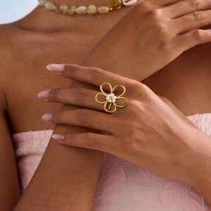 Détail d'une bague fleur en or 18K ornée de perles centrées sur la main d'un mannequin