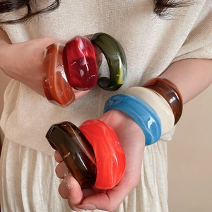 Close-up of wide acrylic resin bangles with marble texture in multiple colors
