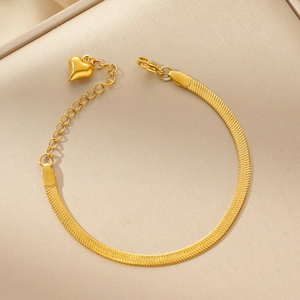 Detailed close-up of a golden heart pendant on a polished snake chain bracelet
