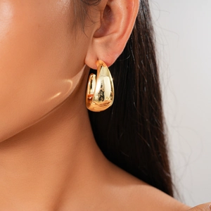 Close-up of chunky gold water drop earrings with mirror finish on model ear