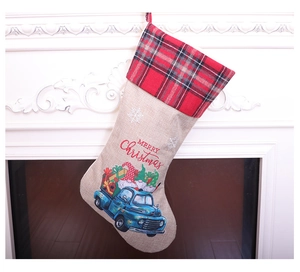 Linen Christmas stocking with blue truck and gnome print hanging on a white fireplace