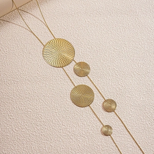 Detail of tiered gold necklace with hammered texture round charms on a textured base