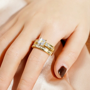 Driedelige gouden ringenset met vierkante prinsesgeslepen steen op zijden stof