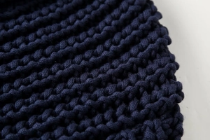 Gros plan sur un tricot bleu marine à grosses mailles montrant la texture de la laine