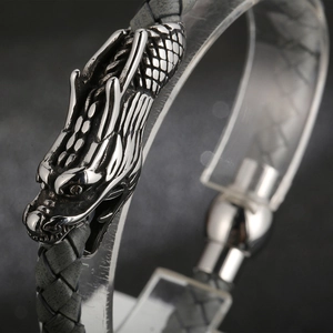 Detailed view of grey braided leather bracelet with an intricate silver dragon head clasp