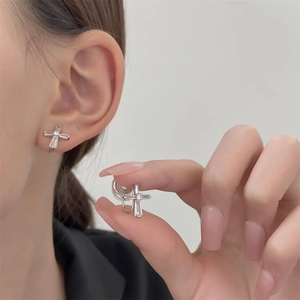 Macro shot of silver cross earrings featuring transparent rectangular zirconia stones