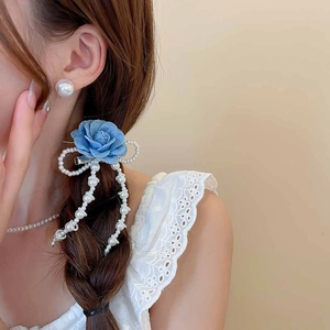 Detail of blue denim rose hair clip with pearl fringe and large pearl earrings on model