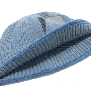 Close-up of blue-grey knit beanie featuring geometric diamond patterns and ribbed texture