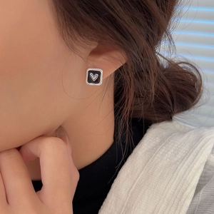 Orecchini a perno quadrati in argento dorato con cuore in smalto nero indossati dal modello