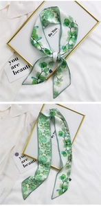 Detailed close-up of a floral silk twilly scarf with green leaf print and fine stitching