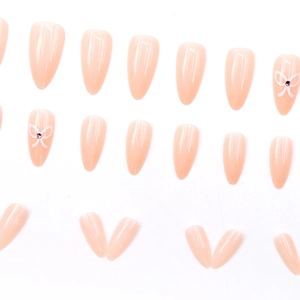 Faux ongles amande roses avec des nœuds blancs et des strass pour un style doux