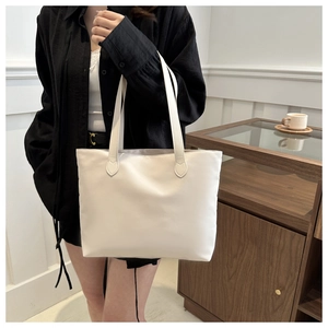 Minimalist white nylon tote bag shown in a professional lifestyle hand-carry model pose