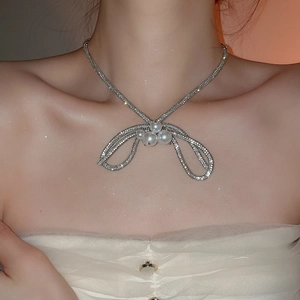 Close-up of elegant silver bow necklace with sparkling diamonds and pearls on model