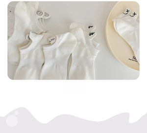 Detailed embroidery of cartoon faces and cross eyes on white low cut cotton socks