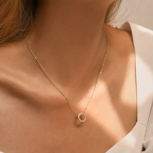 Close-up of gold chain necklace with sparkling pave cubic zirconia circle pendant worn on neck