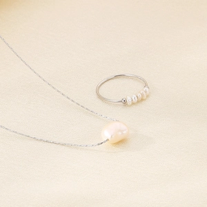 Elegant freshwater pearl necklace and beaded ring set displayed on premium beige silk fabric